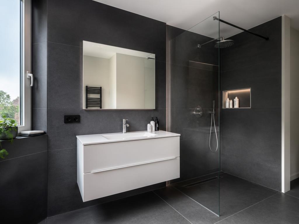 Salle de bain moderne avec carrelage anthracite, meuble suspendu blanc et douche à l'italienne vitrée